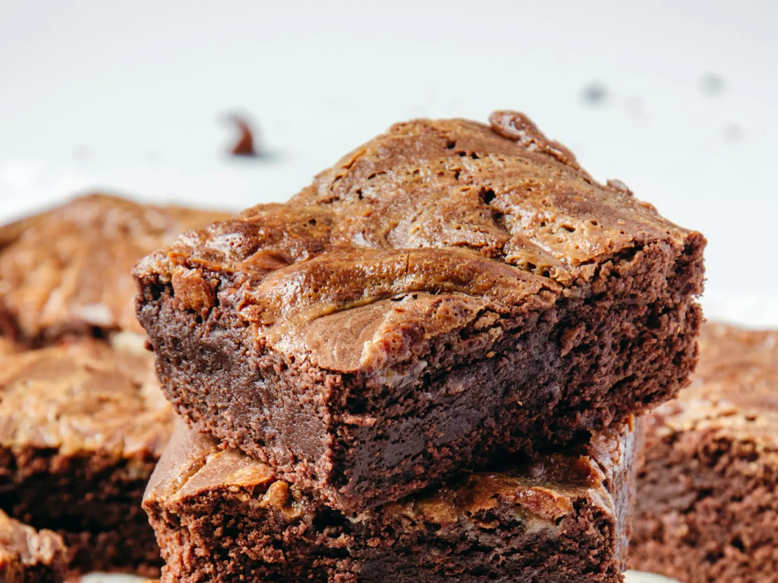 Stack of fudgy chocolate brownies on a white plate